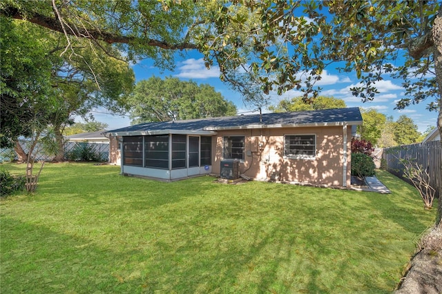 back of property with a sunroom, central AC unit, and a lawn