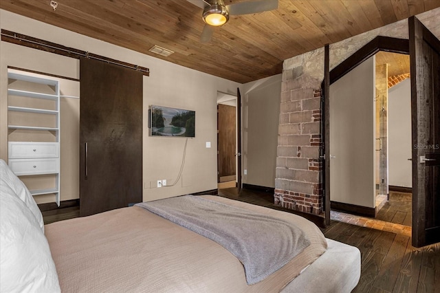 bedroom featuring a barn door, ceiling fan, dark hardwood / wood-style floors, and wooden ceiling