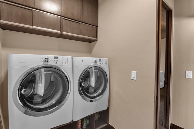 washroom featuring washing machine and dryer and cabinets