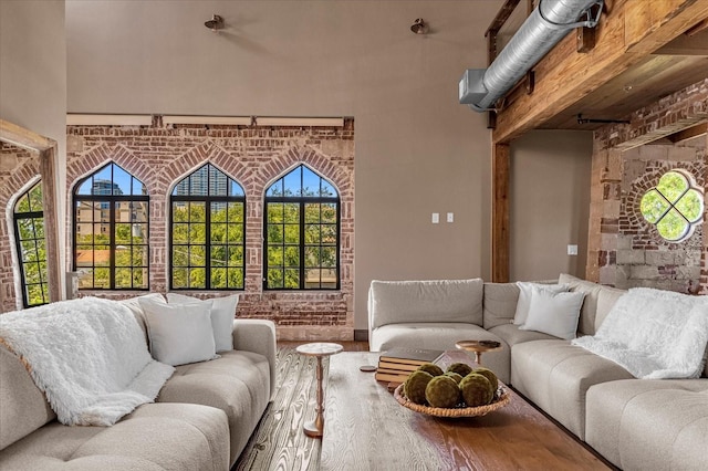 living room featuring brick wall, beam ceiling, and hardwood / wood-style flooring