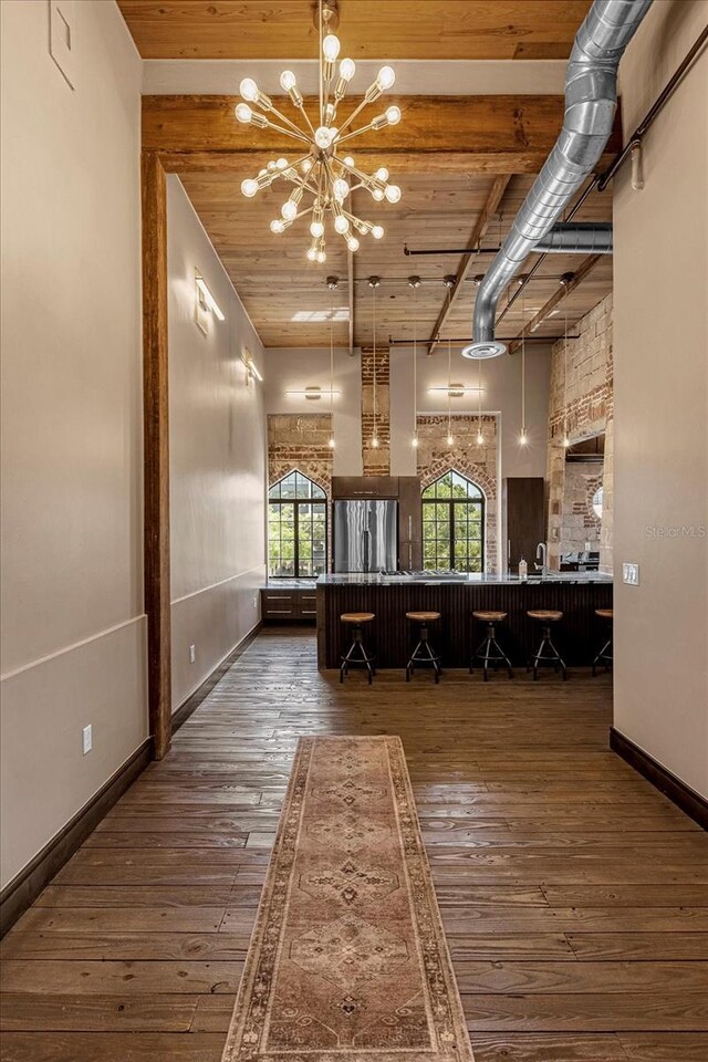 interior space featuring beamed ceiling, wood ceiling, a high ceiling, a chandelier, and dark hardwood / wood-style floors