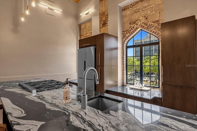 kitchen featuring stone countertops, sink, a high ceiling, stainless steel fridge, and hardwood / wood-style flooring