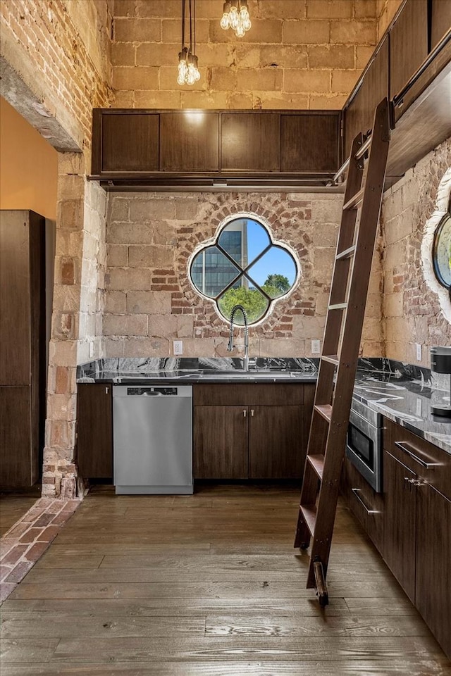 kitchen featuring brick wall, hardwood / wood-style floors, dishwasher, and decorative light fixtures