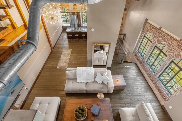 living room featuring wood-type flooring, a towering ceiling, and a notable chandelier