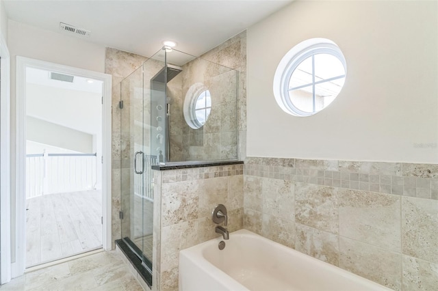 bathroom with tile walls, a wealth of natural light, and independent shower and bath