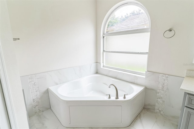 bathroom with a tub to relax in, vanity, plenty of natural light, and tile walls