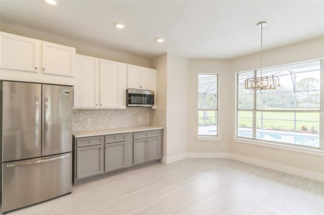 kitchen featuring gray cabinetry, decorative light fixtures, appliances with stainless steel finishes, a chandelier, and white cabinetry