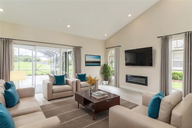 living room with a glass covered fireplace, recessed lighting, and high vaulted ceiling