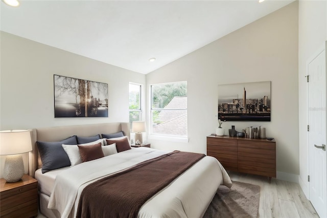 bedroom featuring vaulted ceiling, light wood-style flooring, and baseboards