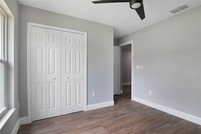 unfurnished bedroom with a closet, dark hardwood / wood-style floors, and ceiling fan