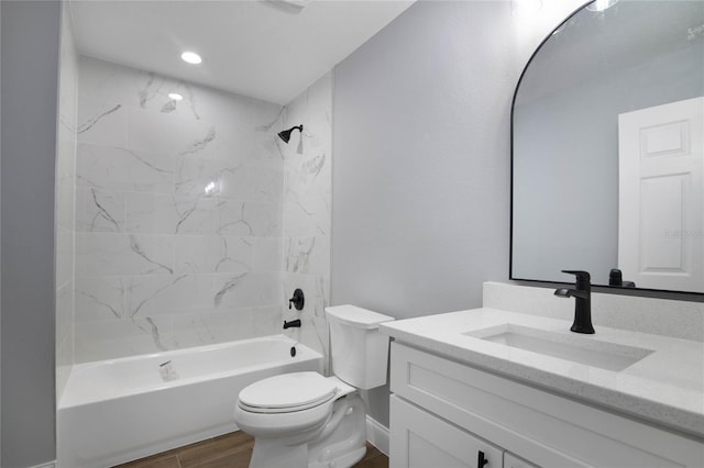 full bathroom featuring vanity, hardwood / wood-style floors, tiled shower / bath combo, and toilet