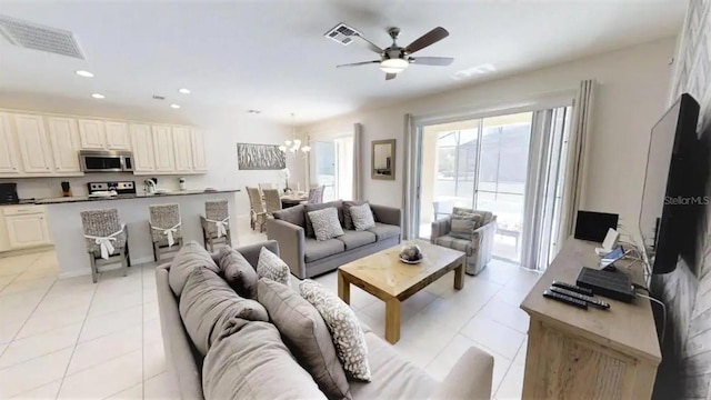 tiled living room with ceiling fan with notable chandelier