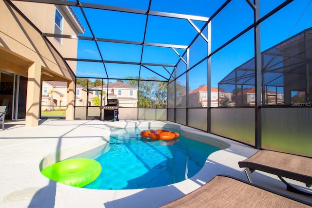 view of pool with a grill, glass enclosure, and a patio area