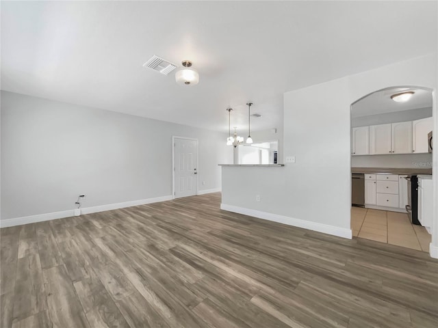 unfurnished living room featuring wood-type flooring and a chandelier