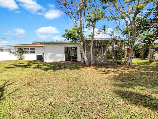 rear view of property featuring central AC unit and a yard