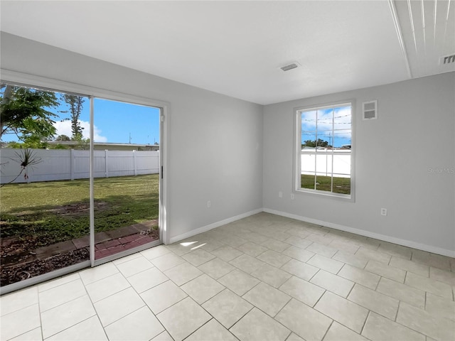 empty room with light tile patterned flooring and plenty of natural light