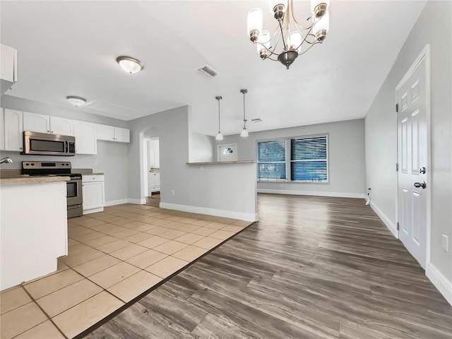 kitchen featuring pendant lighting, light wood-type flooring, appliances with stainless steel finishes, and white cabinetry