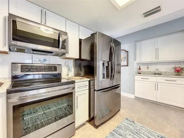 kitchen featuring stainless steel appliances, backsplash, visible vents, and white cabinets