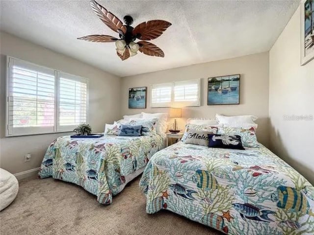 carpeted bedroom with a ceiling fan, multiple windows, a textured ceiling, and baseboards