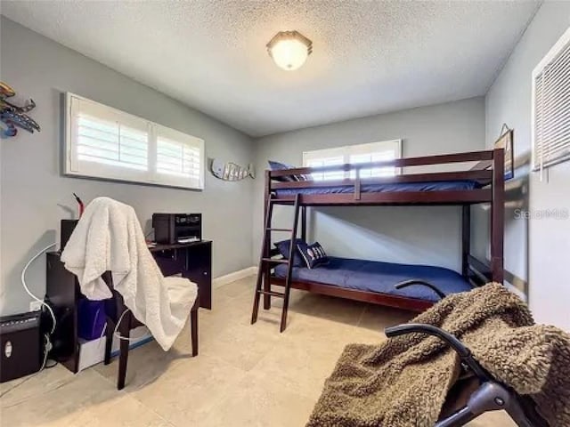 bedroom featuring a textured ceiling, multiple windows, and baseboards