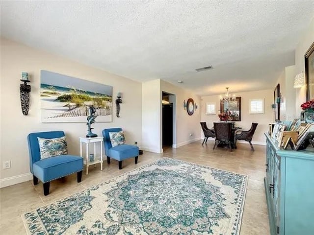 sitting room with a chandelier, visible vents, a textured ceiling, and baseboards