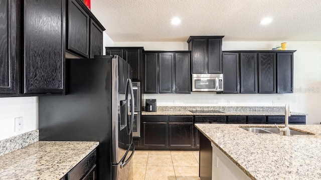 kitchen featuring appliances with stainless steel finishes, a textured ceiling, light tile patterned floors, and sink