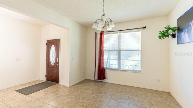 tiled entryway with a chandelier, a healthy amount of sunlight, and a textured ceiling