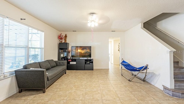 tiled living room with ceiling fan and a textured ceiling