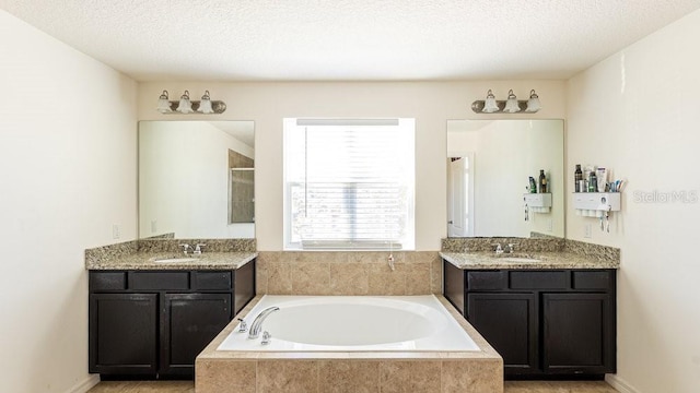 bathroom with a relaxing tiled tub, a textured ceiling, and vanity