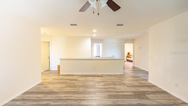 empty room with ceiling fan and light hardwood / wood-style flooring