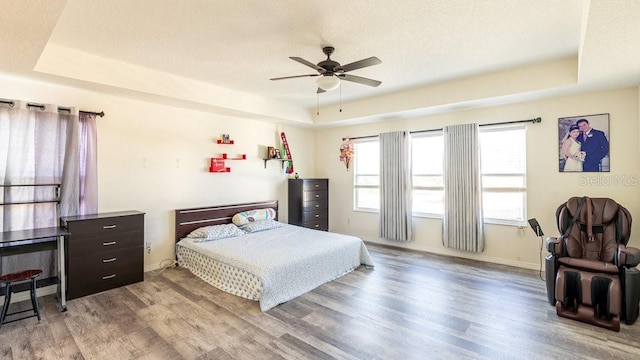 bedroom featuring a raised ceiling, light hardwood / wood-style flooring, and ceiling fan