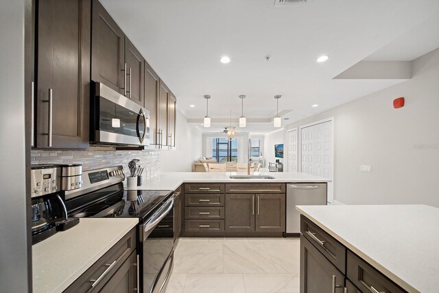 kitchen with light tile patterned floors, kitchen peninsula, appliances with stainless steel finishes, decorative backsplash, and sink