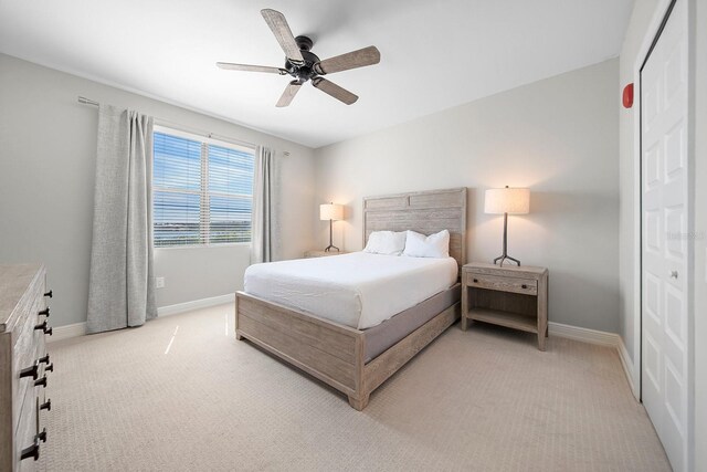 bedroom featuring light colored carpet, a closet, and ceiling fan