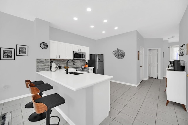 kitchen with stainless steel appliances, backsplash, a kitchen bar, light tile floors, and sink