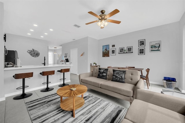 living room featuring ceiling fan, sink, and light tile floors