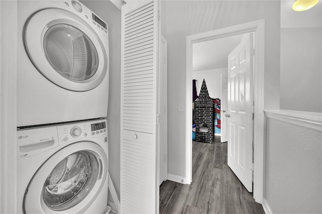 laundry room featuring dark wood-type flooring and stacked washer / dryer