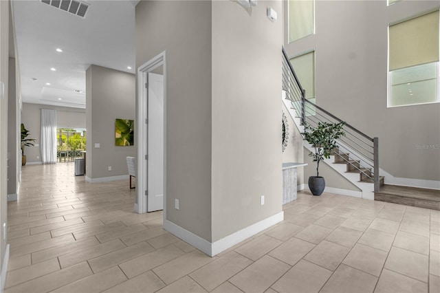 stairway with a towering ceiling and light tile floors