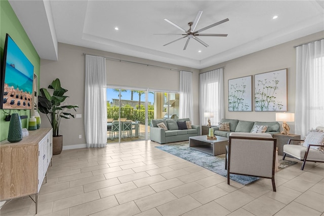 tiled living room featuring ceiling fan and a tray ceiling