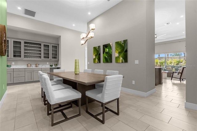 dining space featuring ceiling fan with notable chandelier and light tile flooring