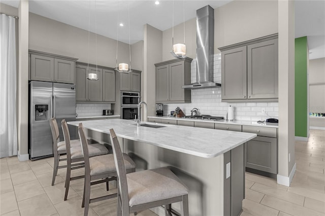 kitchen featuring appliances with stainless steel finishes, backsplash, hanging light fixtures, wall chimney exhaust hood, and sink