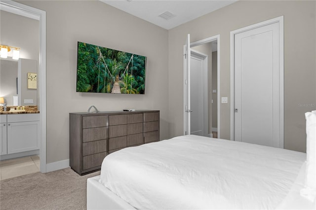 bedroom with connected bathroom and light carpet