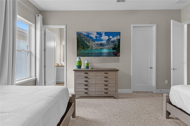 carpeted bedroom featuring ensuite bathroom and multiple windows