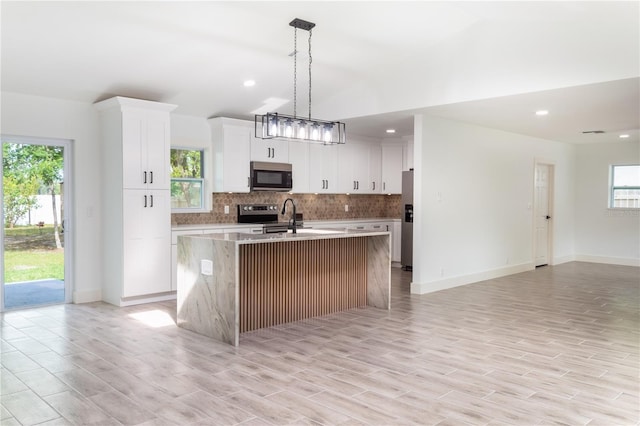 kitchen featuring a kitchen island with sink, a wealth of natural light, stainless steel appliances, and light hardwood / wood-style floors