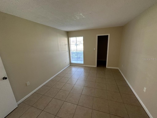 tiled empty room with a textured ceiling