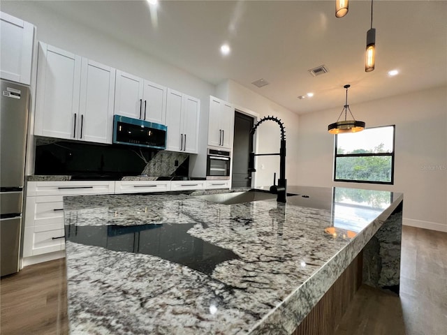 kitchen featuring decorative light fixtures, dark wood-type flooring, white cabinetry, backsplash, and stainless steel appliances