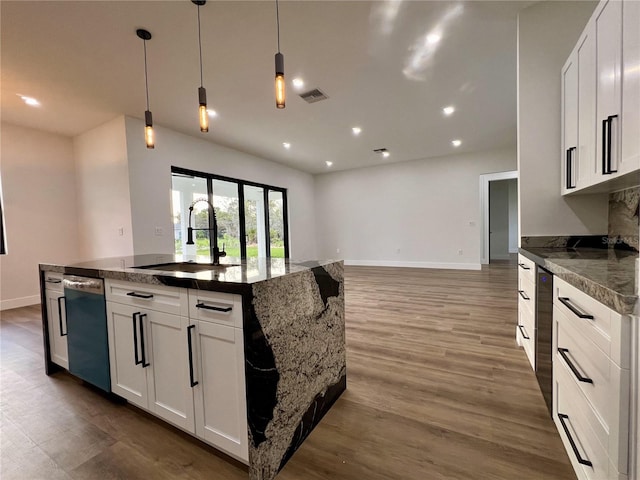 kitchen featuring dishwashing machine, a kitchen island with sink, white cabinetry, sink, and dark hardwood / wood-style flooring