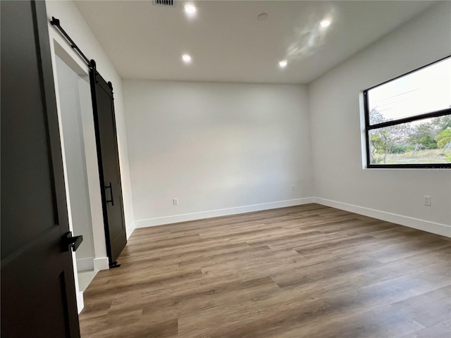 spare room with light wood-type flooring and a barn door