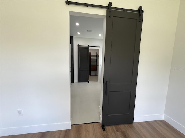 unfurnished room with hardwood / wood-style flooring and a barn door