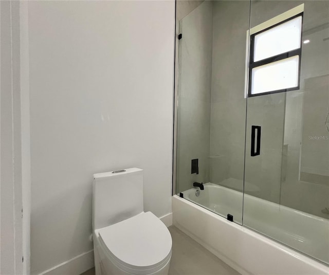 bathroom featuring combined bath / shower with glass door and toilet