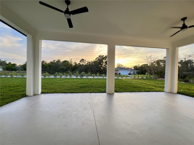 patio terrace at dusk with ceiling fan and a lawn